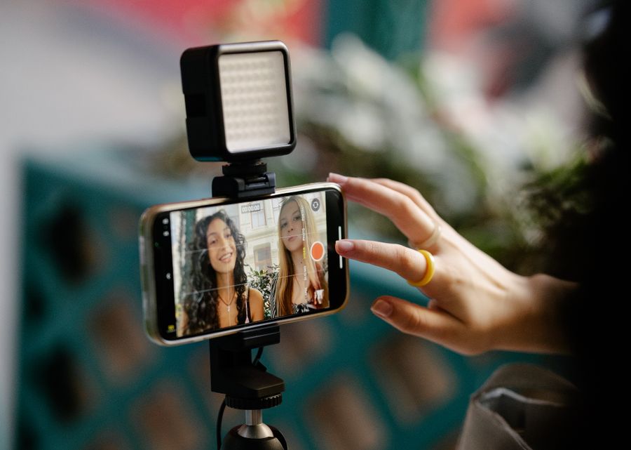 Mulheres utilizando celular e iluminação para produzir um vídeo.